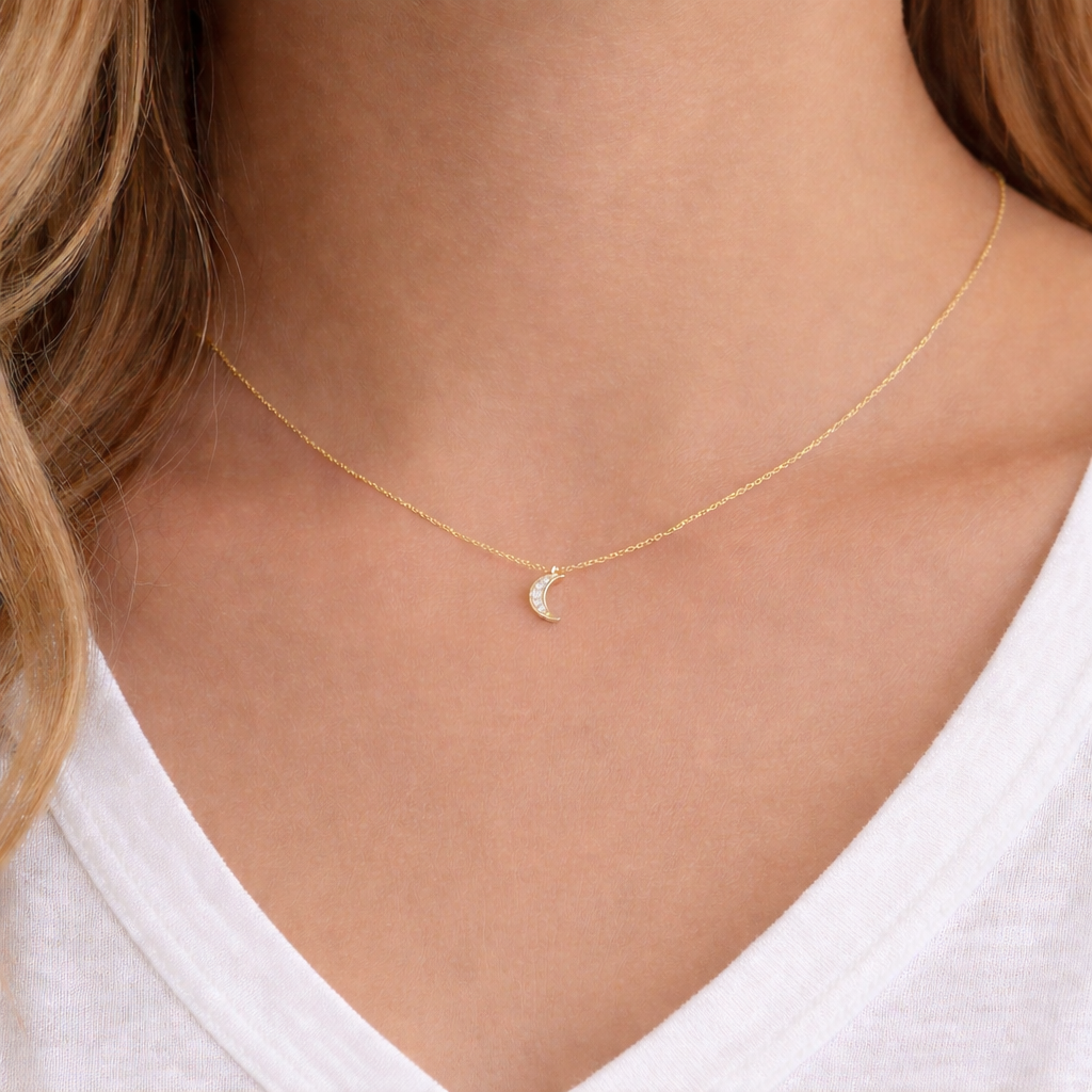 Gold necklace with a moon pendant worn by a person against a neutral background