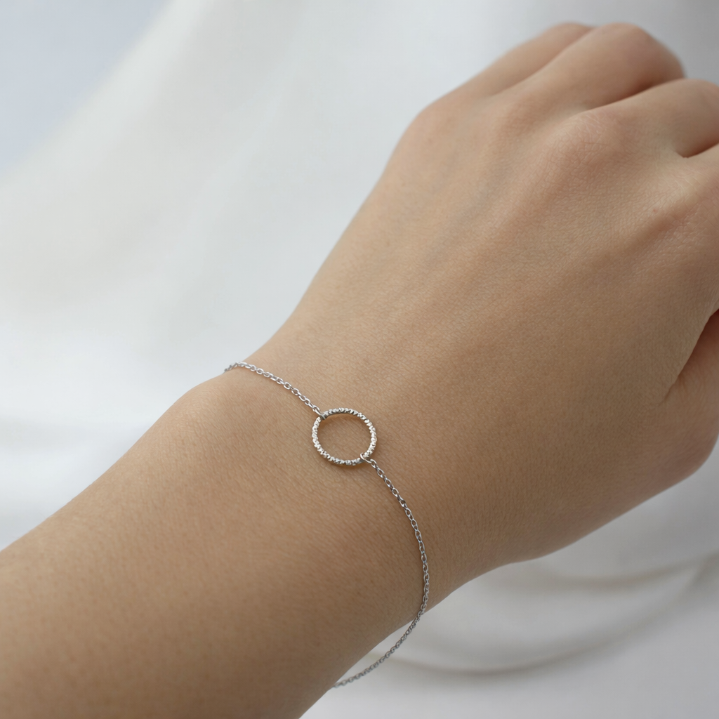 Silver bracelet on a wrist against a light background