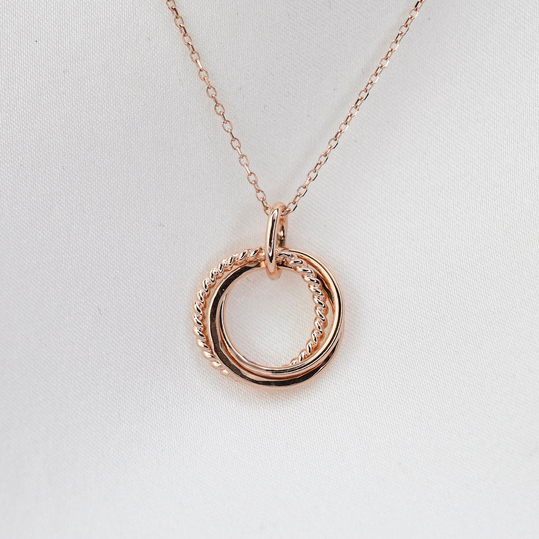 Rose gold necklace with a double circular pendant on a light gray background