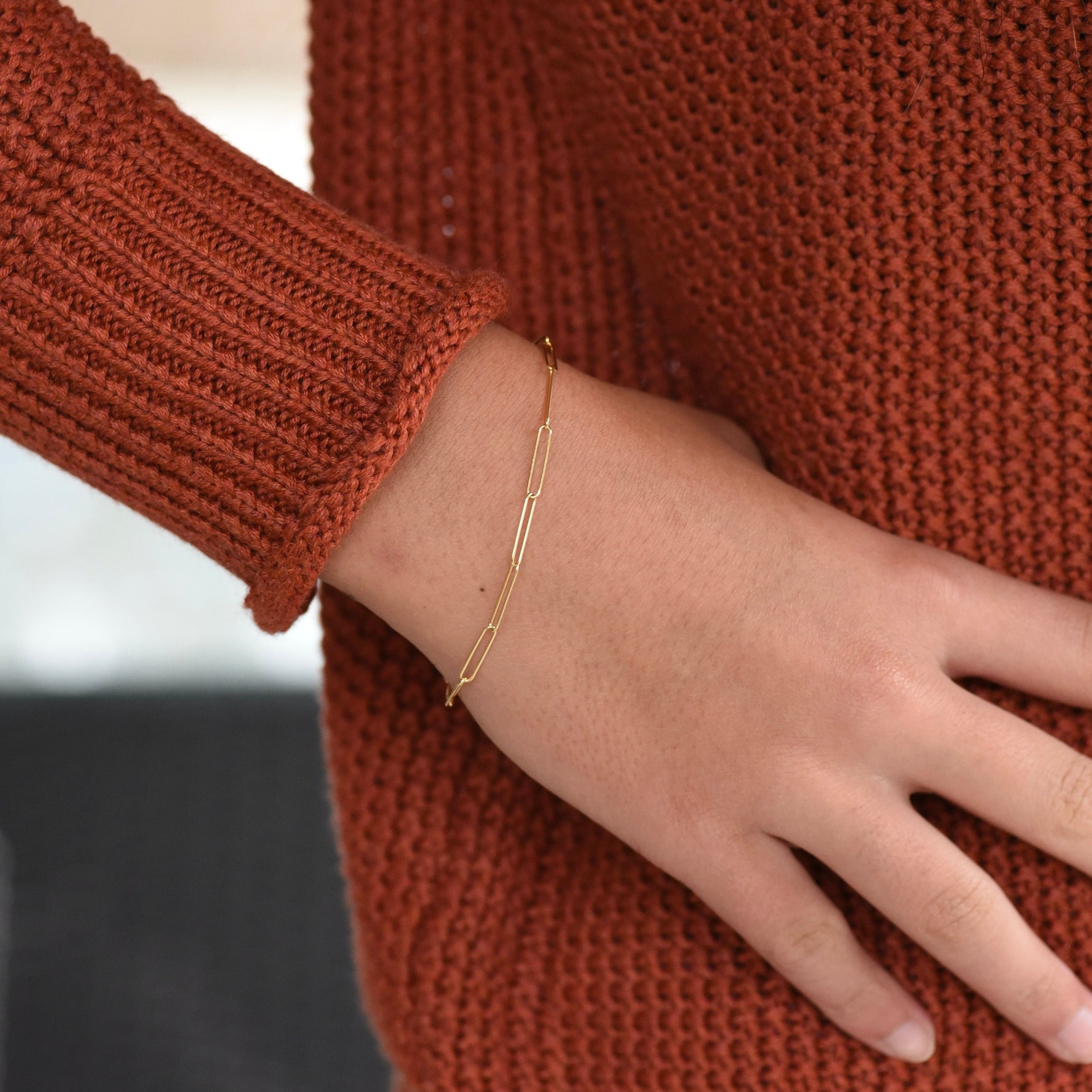 Gold bracelet on a wrist with a brown textured sweater