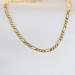 Gold chain necklace on a light gray background