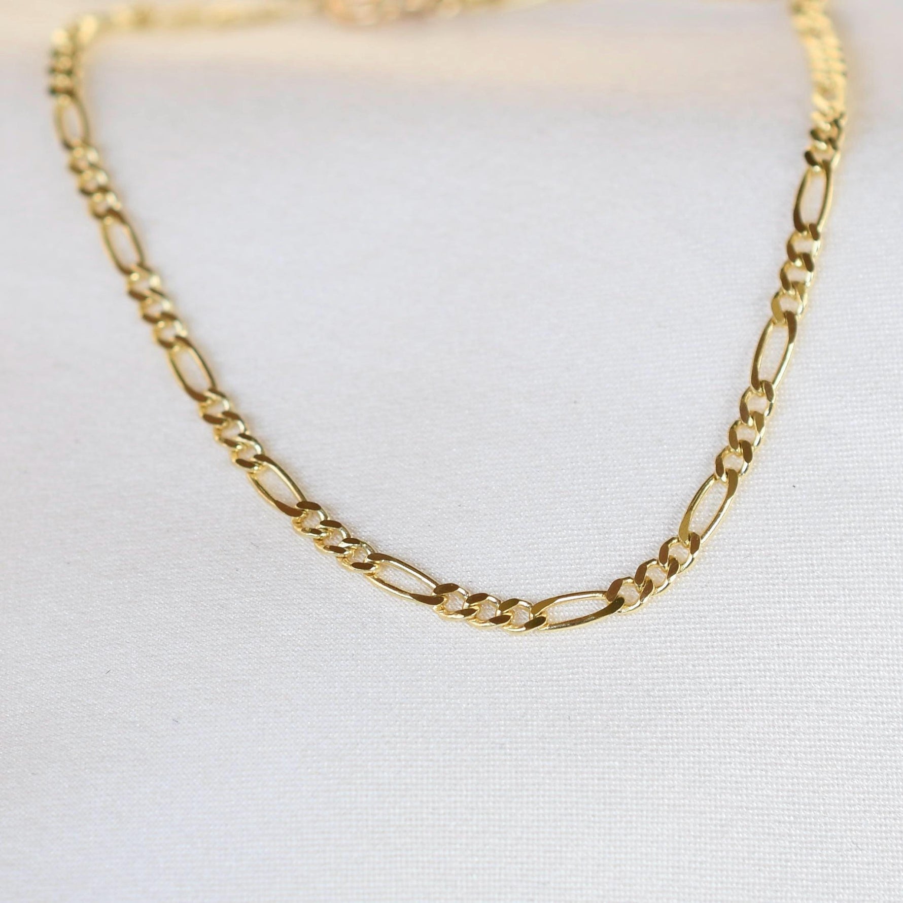 Gold chain necklace on a light gray background