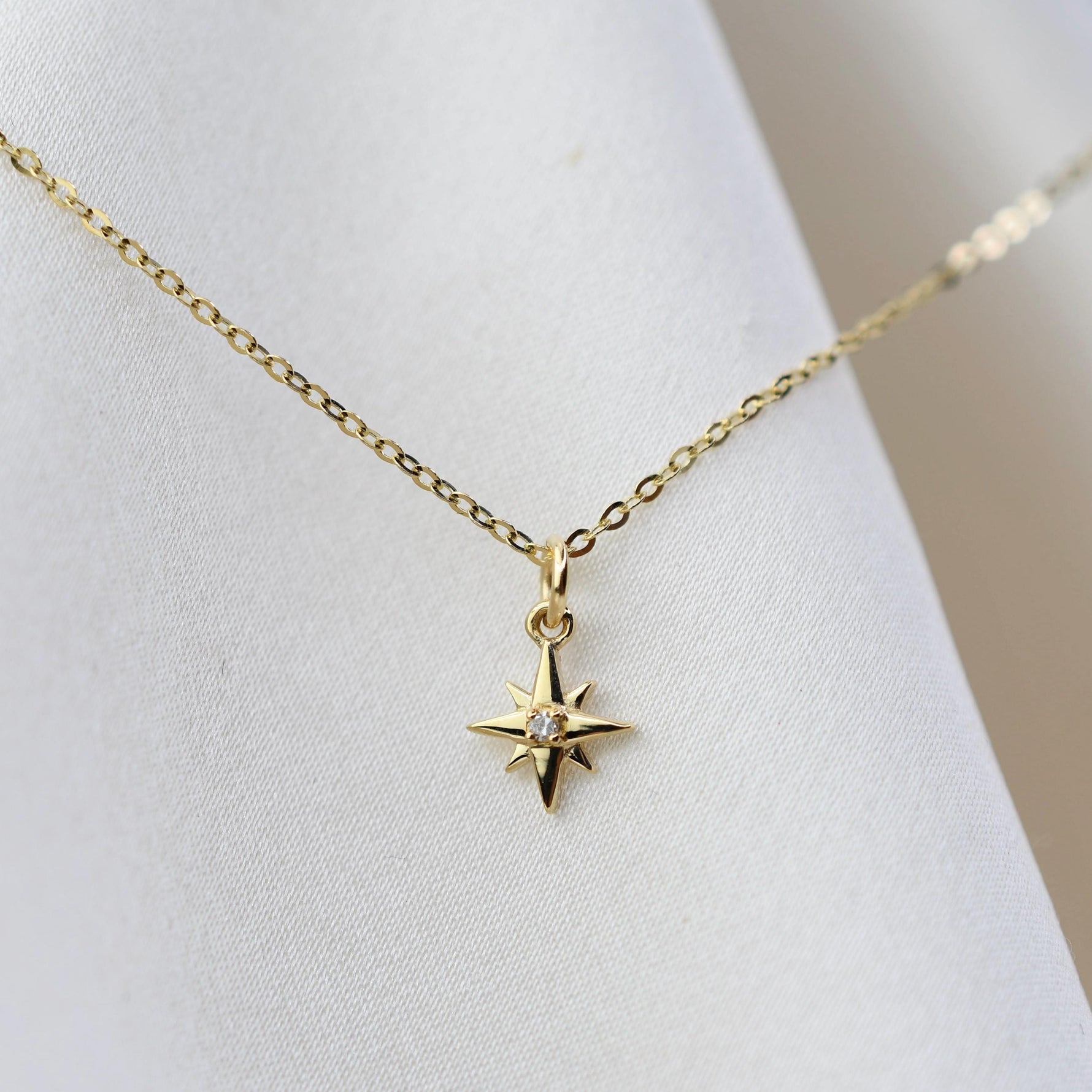 Gold necklace with a star-shaped pendant on a mannequin.