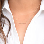 Gold necklace on a person wearing a white shirt