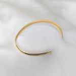 Gold bangle on a white fabric background