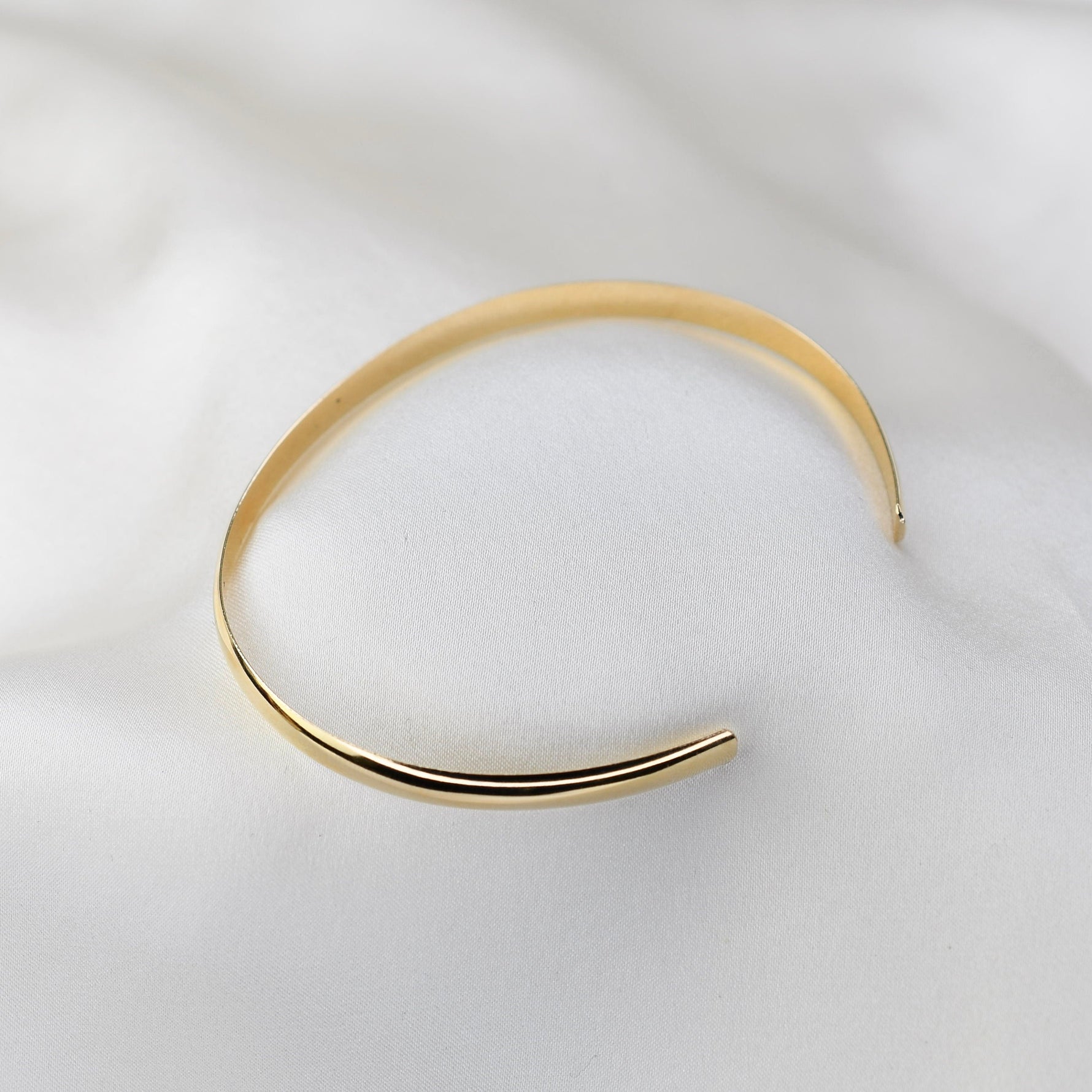 Gold bangle on a white fabric background