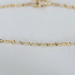 Gold bracelet with small circular links on a light gray background