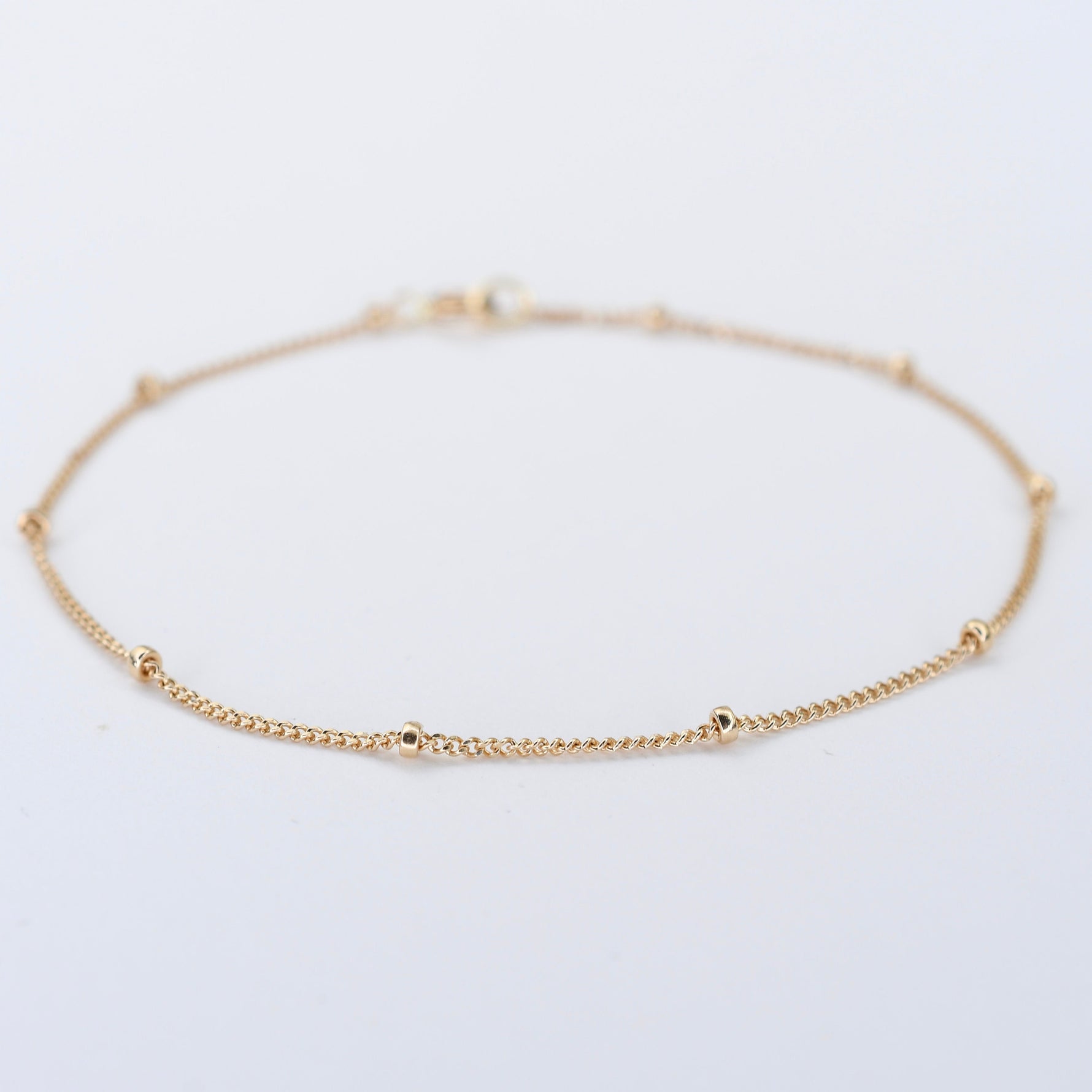 Gold anklet on a light gray background