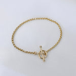 Gold bracelet with a toggle clasp on a light gray background