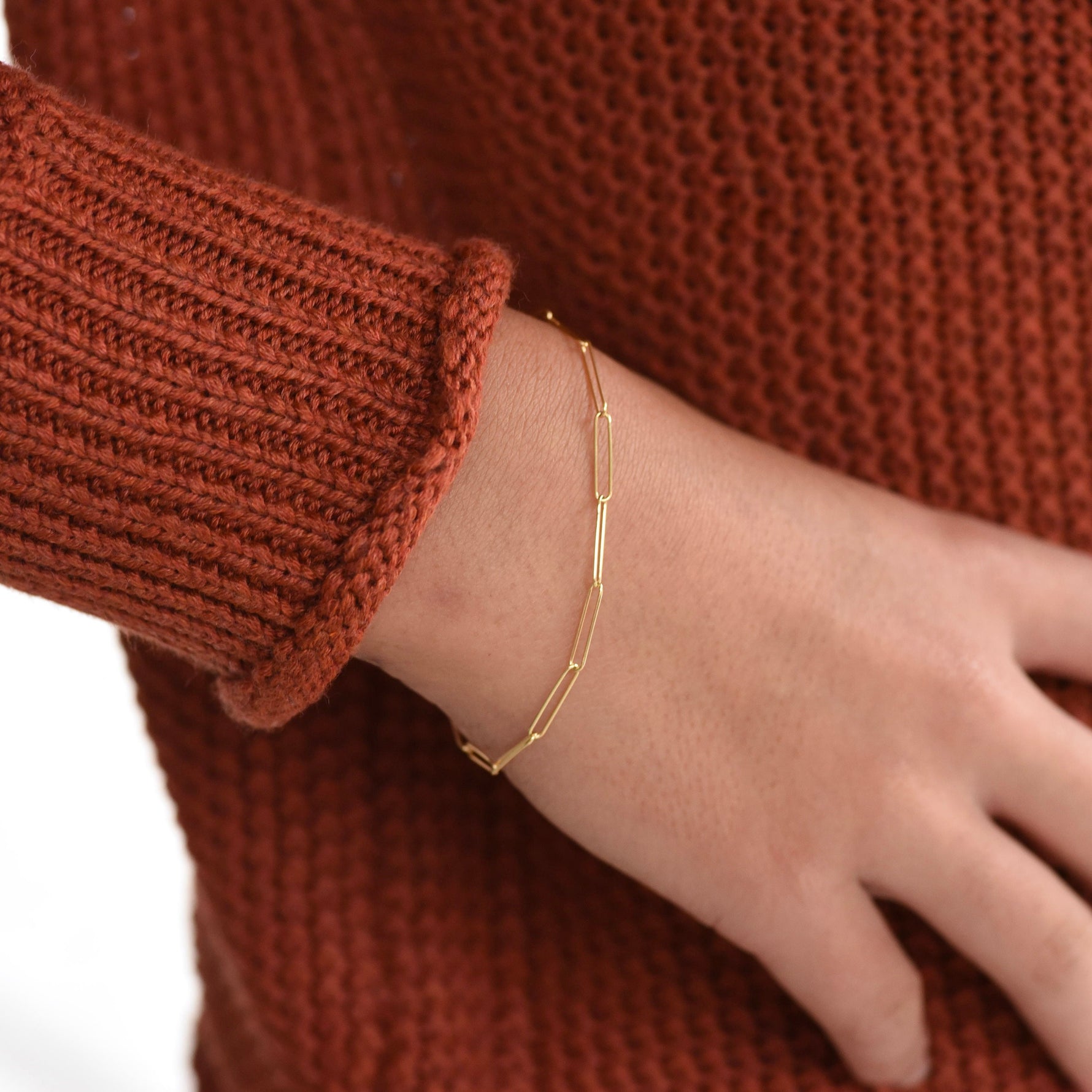 Gold bracelet on a wrist with a brown textured sweater