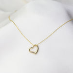 Delicate solid gold heart pendant necklace worn layered