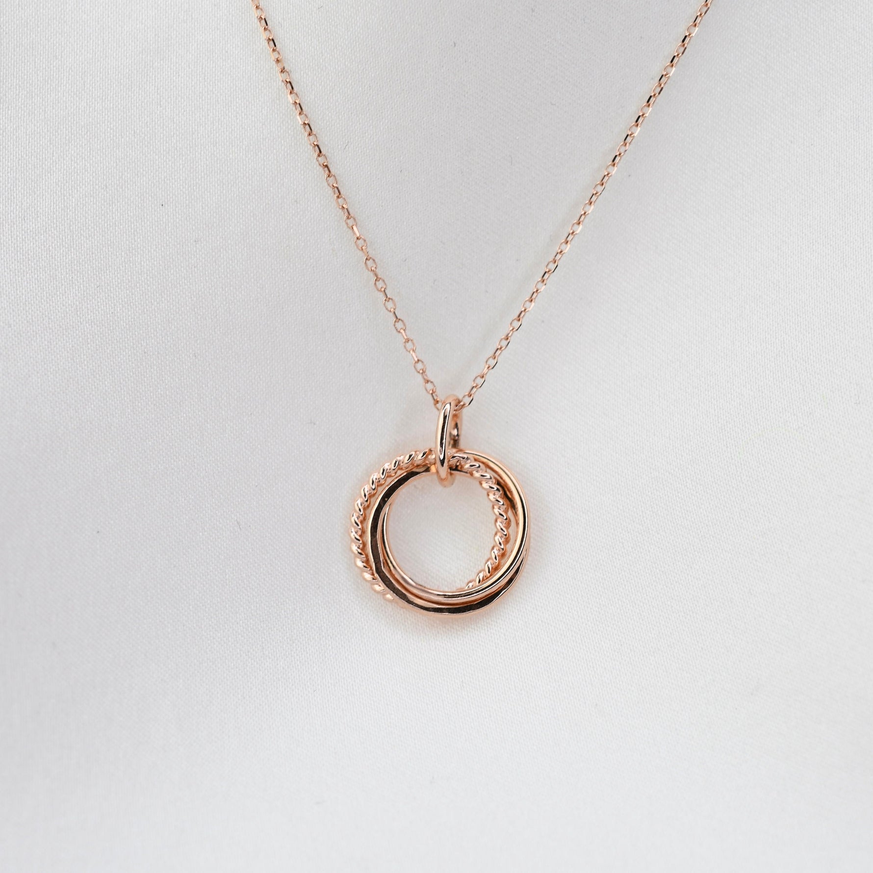 Rose gold necklace with a circular pendant on a light gray background