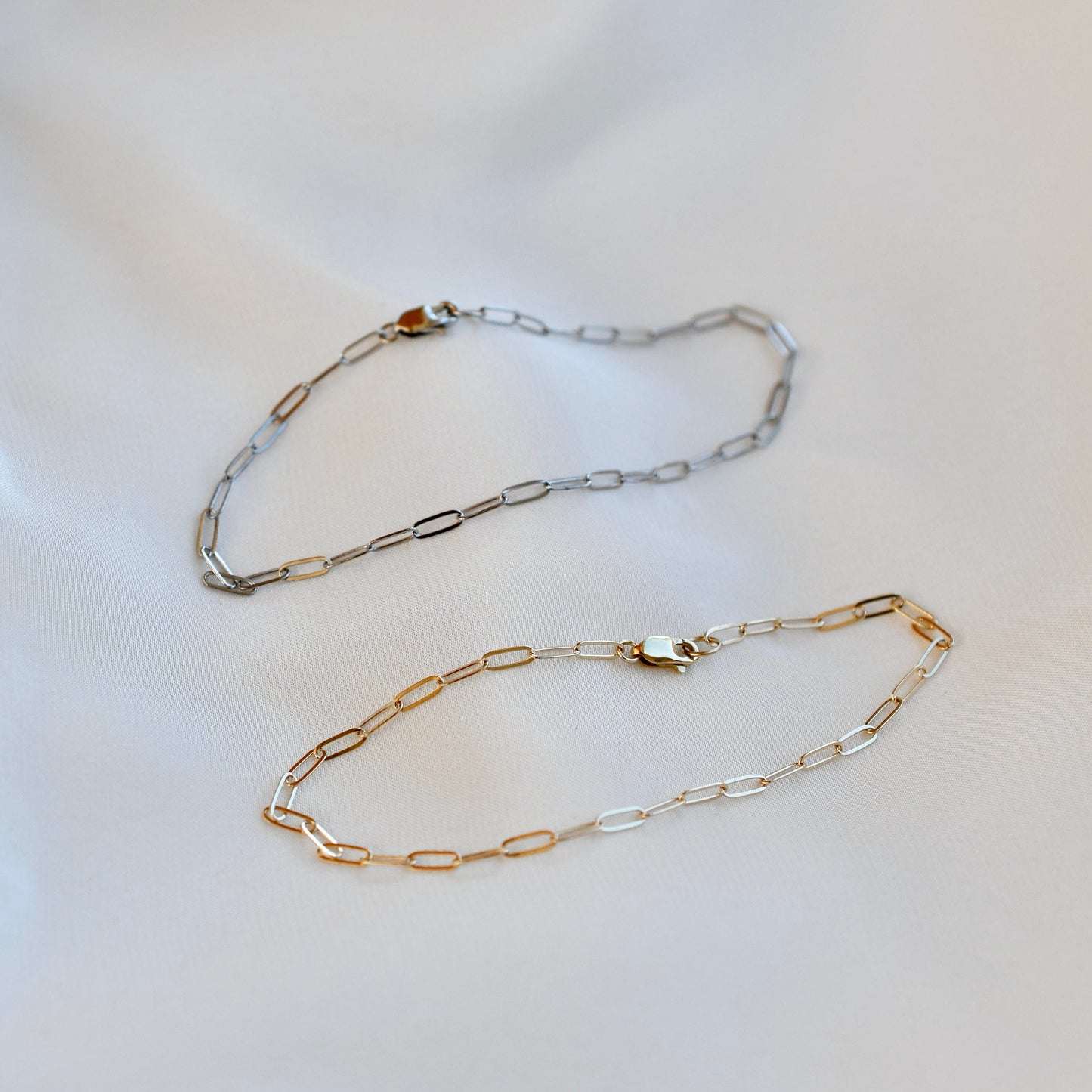 Two gold and silver chain necklaces on a light background