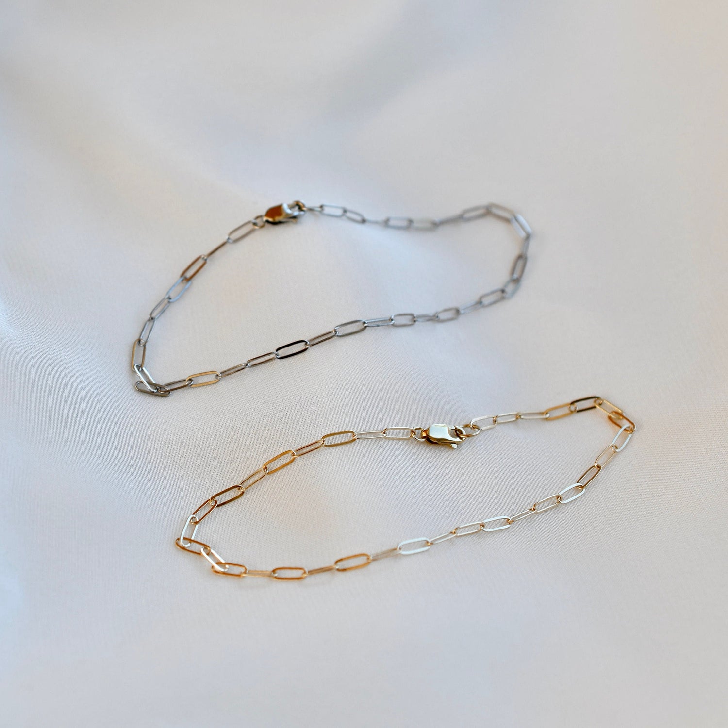 Two gold and silver chain necklaces on a light background
