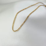 Gold chain necklace on a white fabric background