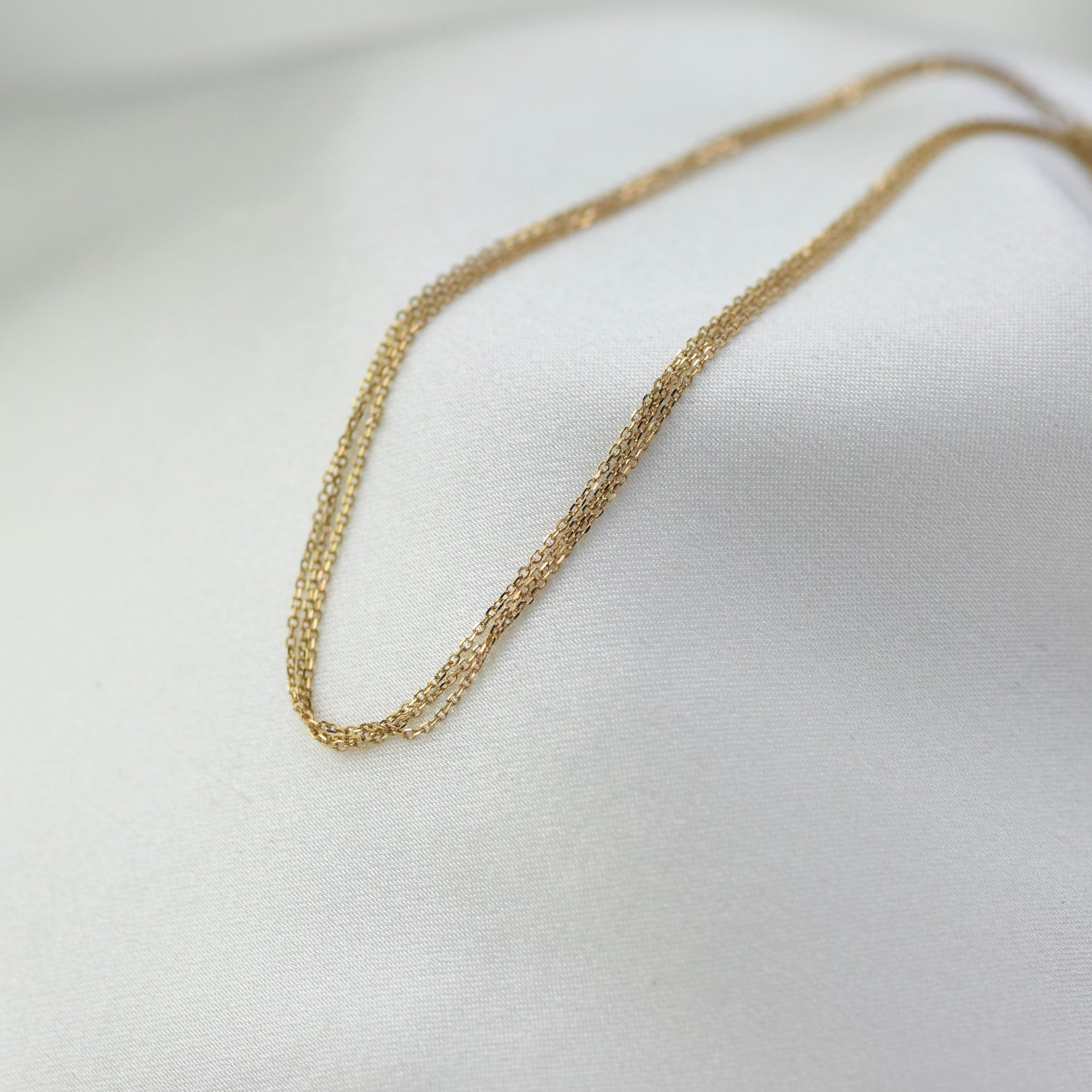 Gold chain necklace on a white fabric background