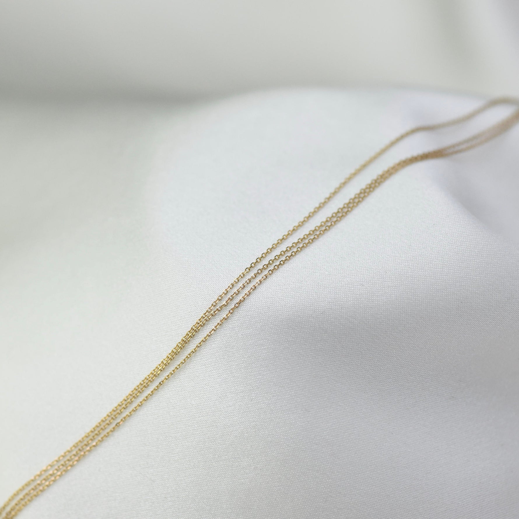 Gold chain necklace on a white fabric background