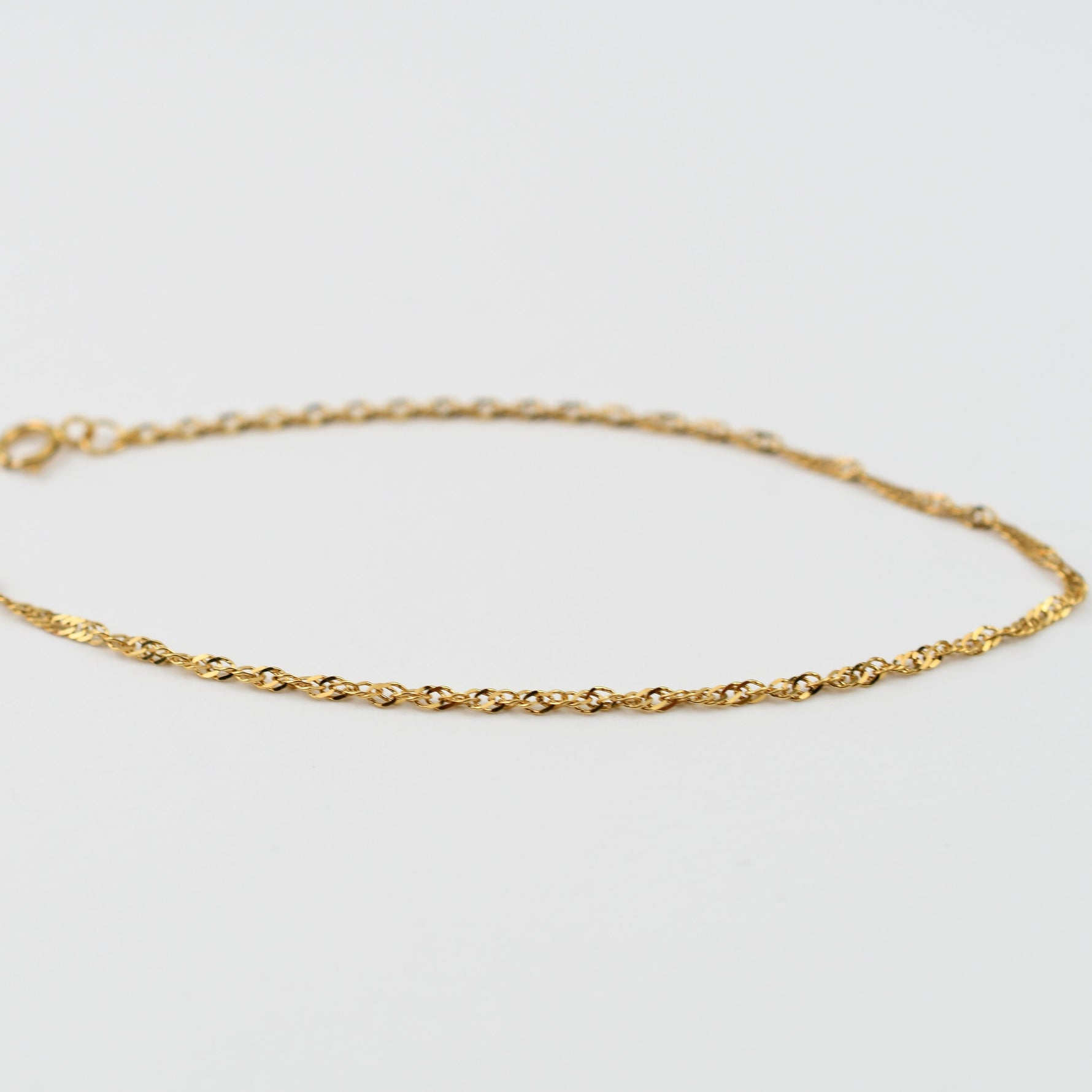 Close up of 14K solid yellow gold 1.8mm Singapore chain bracelet twisted detail
